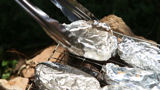 baked potatoes on the grill in foil at the stake