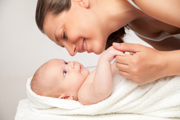 Happy mother with her baby wrapped into towel