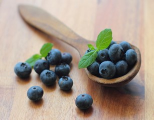 Fresh blueberries on a wooden spoon with mint leafs