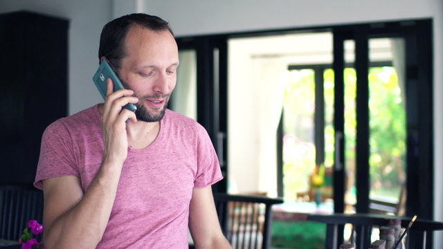 Man talking on cellphone and drinking coffee at home