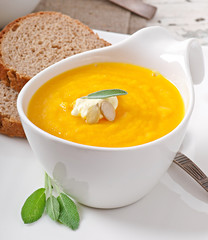Cream of pumpkin soup with sour cream sauce decorated with a lea
