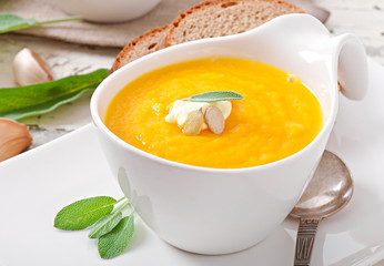 Cream of pumpkin soup with sour cream sauce decorated with a lea