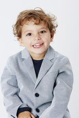 Smart and smiling young boy in suit jacket, portrait.