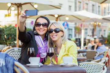 Two female friends making selfie while sitting in cafe