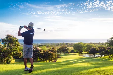 Keuken foto achterwand Golf Man slaat golfbal heuvelafwaarts richting oceaan en horizon