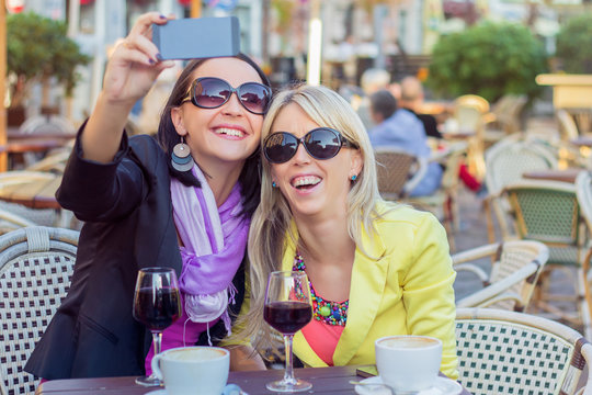 Two cheerful girls taking selfie with mobile phone