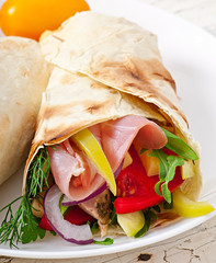 Fresh tortilla wraps with meat and vegetables on plate