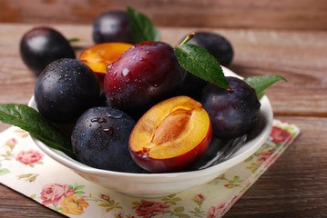 fresh plums in bowl on wooden background