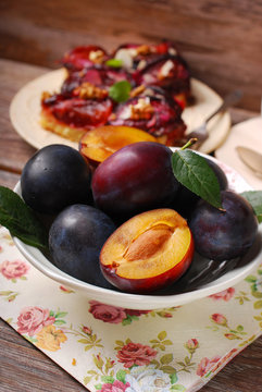 fresh plums in bowl and fruit cake on plate