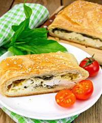 Roll filled with spinach and cheese on board with tomatoes