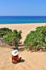 woman with hat watching the sea from a sand dune