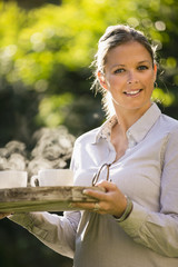 Junge Frau mit Kaffetassen auf Tablette im Hand