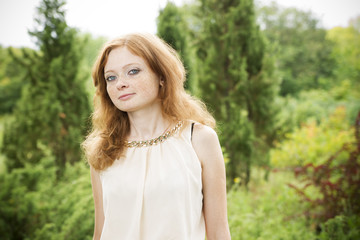 Naklejka premium Portrait of redhead girl with blue eyes on nature
