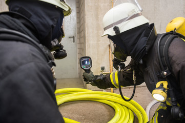 Fototapeta na wymiar Feuerwehrmann hält Wärmebildkamera in Richtung Brandherd