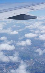 Fototapeta na wymiar view of jet plane wing and white clouds, land below.