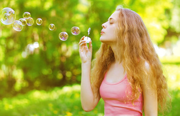 Pretty curly girl blowing soap bubbles having fun outdoors © rohappy