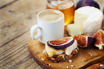 Breakfast setting with coffee, bread, cheese, figs and honey