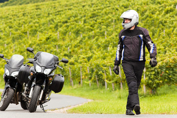 Obraz premium Motorradfahrer mit Helm geht auf der Strasse