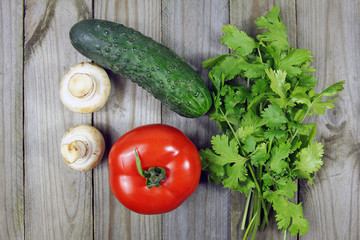 coriander, tomato, mushrooms and cucumber on wooden surface