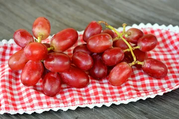 Tapeten tros rode druiven op een geruit kleedje © trinetuzun