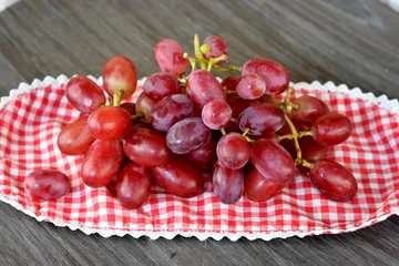 Tapeten tros rode druiven op een geruit kleedje © trinetuzun