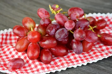 Fotobehang tros rode druiven op een geruit kleedje © trinetuzun