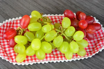 Tapeten tros rode en groene druiven op een geruit kleedje © trinetuzun