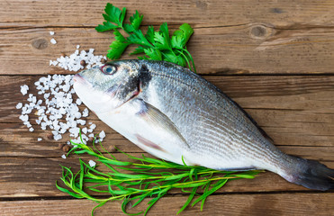 Raw fish gilt-head bream on wooden table with spices