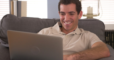 Happy man using laptop on couch