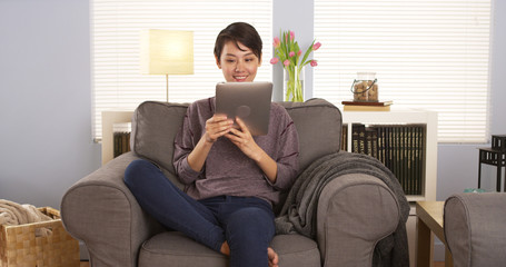 Cute Chinese woman using tablet on couch