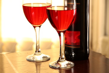 Close-up of glasses with red wine and bottle.