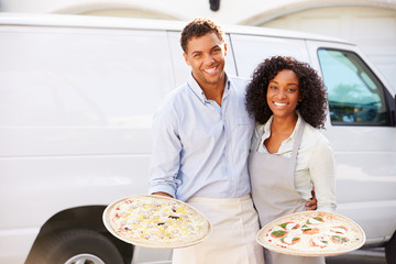 Couple Delivering Pizza Standing In Front Of Van