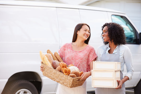 Female Bakers With Bread And Cakes Standing In Front Of Van