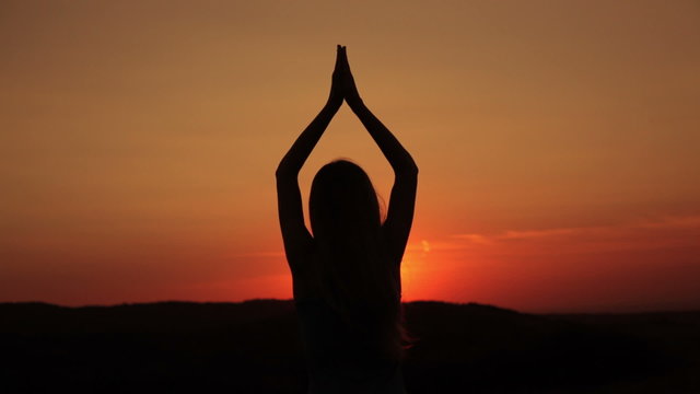 Young woman meditating in the sunset