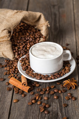 Coffee cup with cinnamon sticks and coffee bag on wooden table