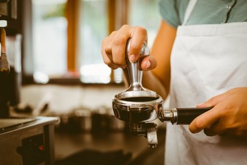 Barista pressing fresh coffee grinds