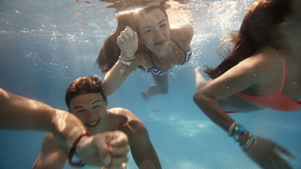 Friends having fun swimming underwater in swimming pool - Powered by Adobe