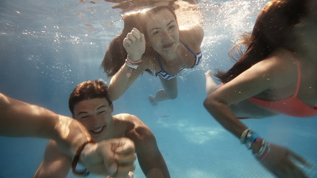 Friends having fun swimming underwater in swimming pool