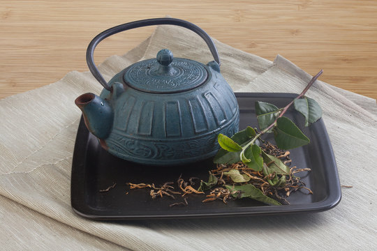 Teapot with tea branch and leaves
