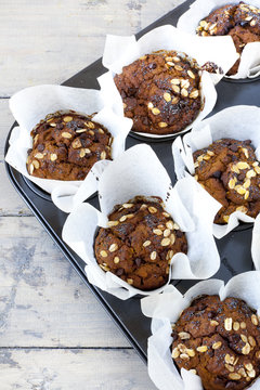 muffins with pumpkin chocolate and oat flakes on baking tray