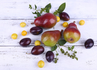 Beautiful ripe pears and plums on wooden table close-up