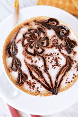 Cup of coffee with cute drawing on table, close up