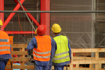 Workers in a construction site with helmet and jacket to prevent accidents