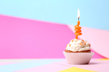 Delicious birthday cupcake on table on bright background