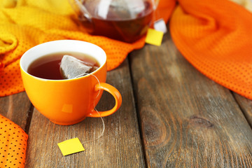 Cup of tea, teapot and tea bags on wooden table close-up