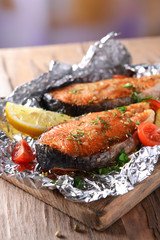 Tasty baked fish in foil on table close-up
