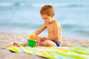 cute kid playing with toys in sand on the beach