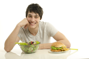 Man holding in front a bowl of salad and a big hamburger