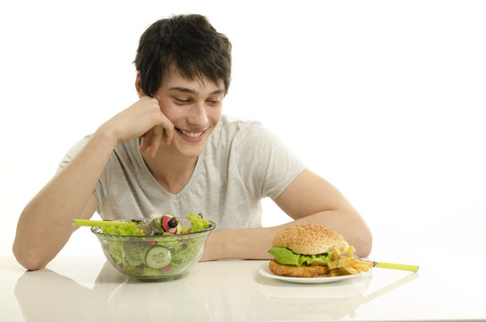 Man holding in front a bowl of salad and a big hamburger