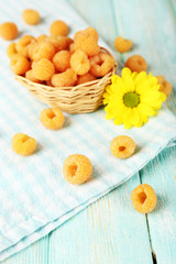Fototapeta na wymiar Yellow raspberries in basket and wildflower